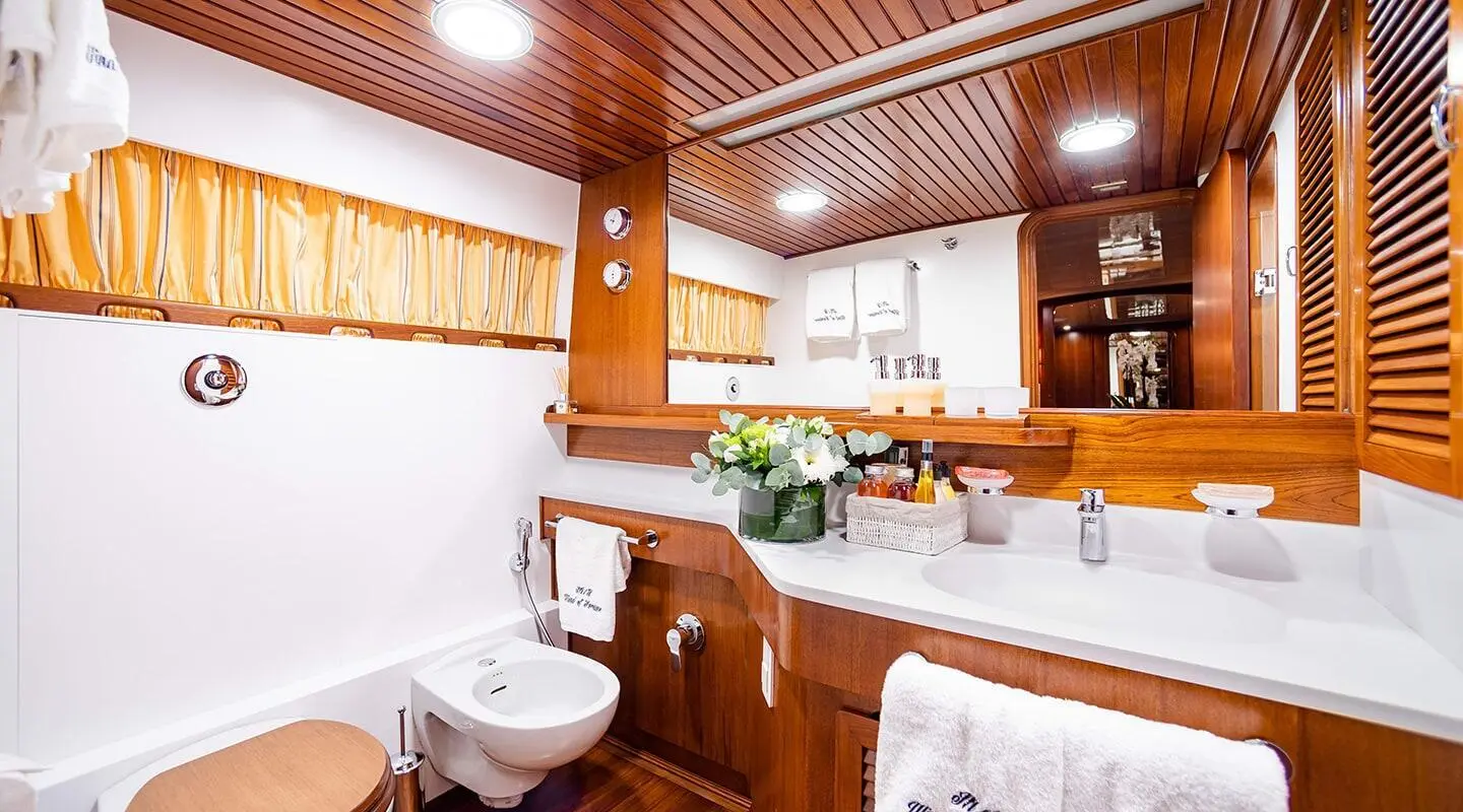 Interior of a yacht with polished wooden cabinets, seating, and a small dining area