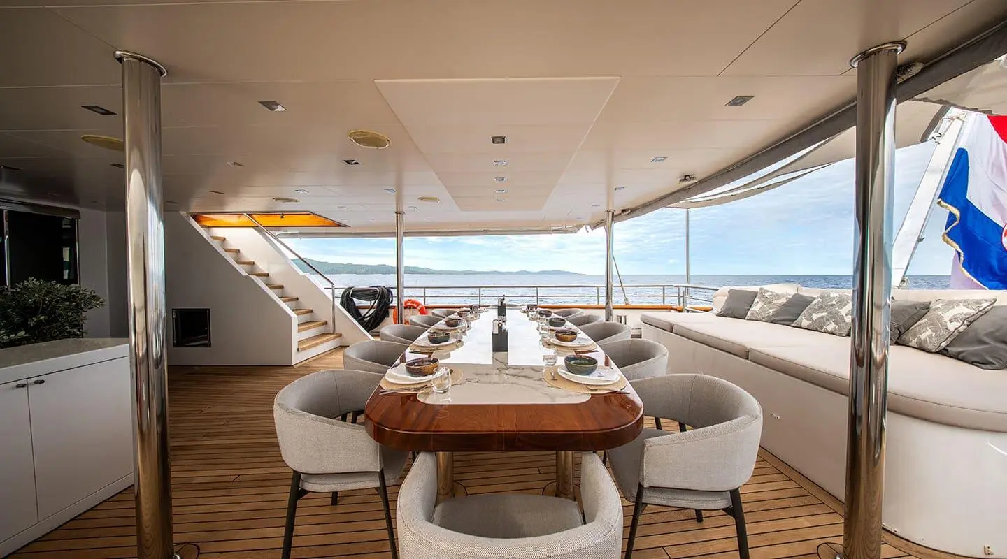 Dalmatino yacht dining area on deck with sunset ocean view and table setting