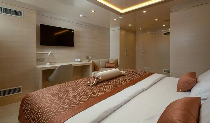 Love Story yacht cabin interior with queen bed, warm wood tones, and plush cushions