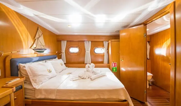 Cozy yacht cabin with two single beds, wooden paneling, and overhead lighting