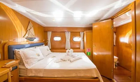 Cozy yacht cabin with two single beds, wooden paneling, and overhead lighting
