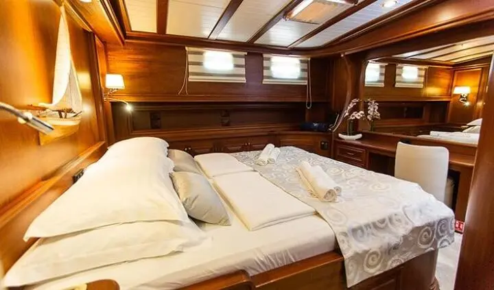 Dolce Vita yacht cabin with two single beds, warm wood paneling, and porthick windows