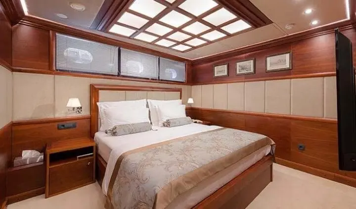 Master cabin with king bed, beige bedding, wood paneling, and windows