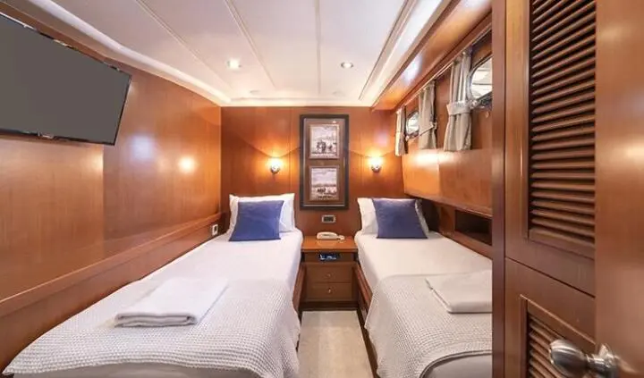 Arabella yacht cabin with two single beds, wood paneling, and overhead storage