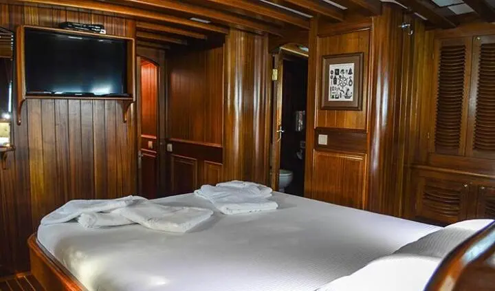 Master cabin with wooden paneling, bed, pillows, and built-in cabinetry