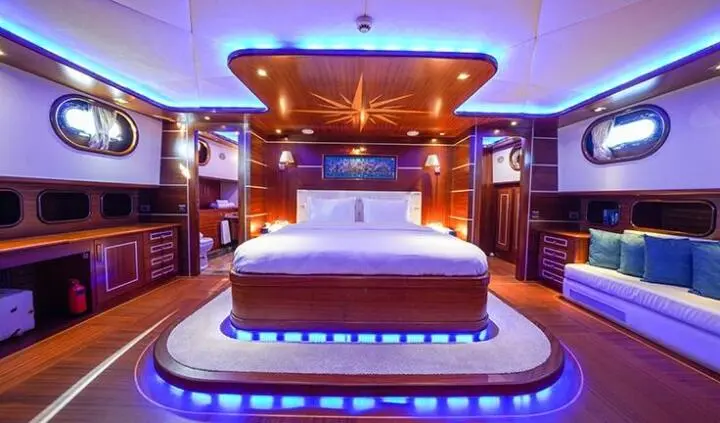 Master cabin with king bed, ensuite, warm lighting, wooden cabinetry, blue deck lighting