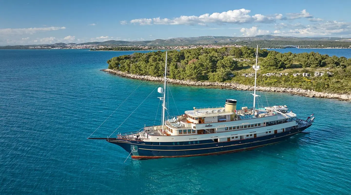 Casablanca yacht anchored near rocky shore with calm blue sea and clear sky