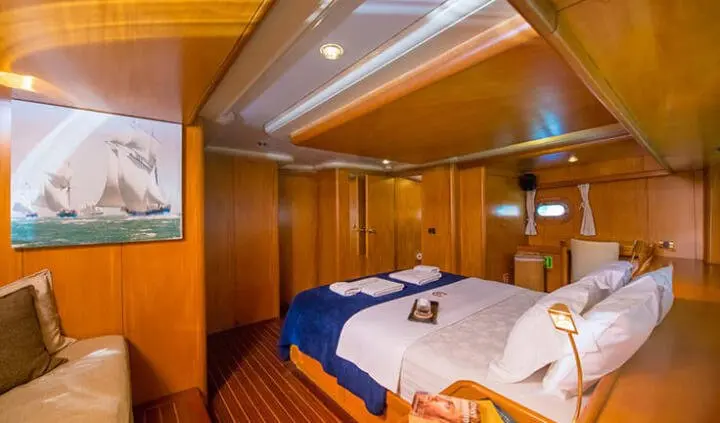 Cozy yacht master cabin with a large king bed, wood paneling, and ensuite area