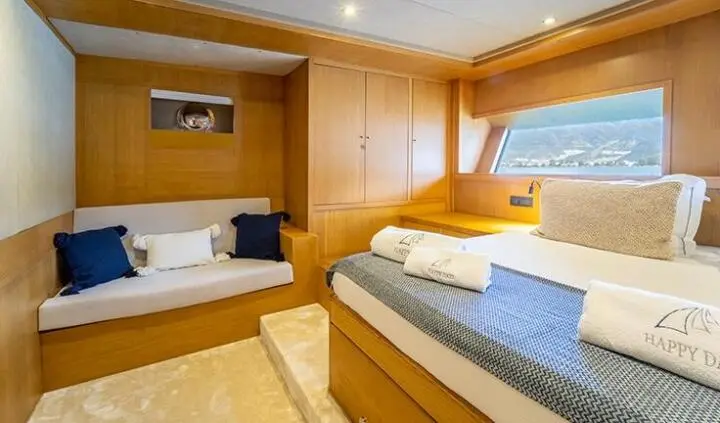 Master cabin with two beds, wood paneling, and built-in storage on a yacht