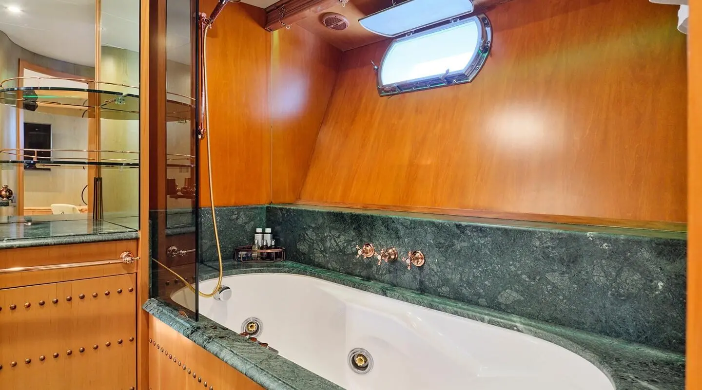 Interior view of luxury Mobius yacht bathroom with tub, wood panels, and porthole