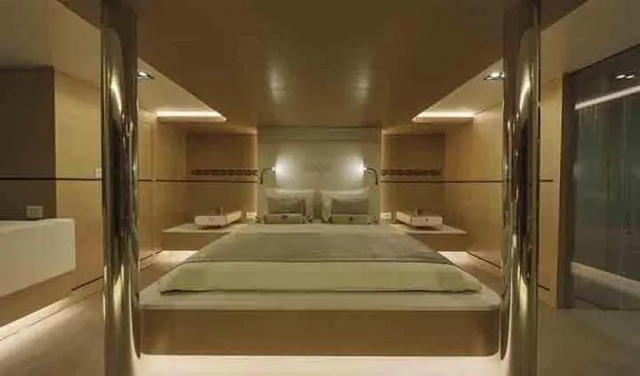 Omnia yacht cabin with a large king bed, ensuite area visible and warm lighting