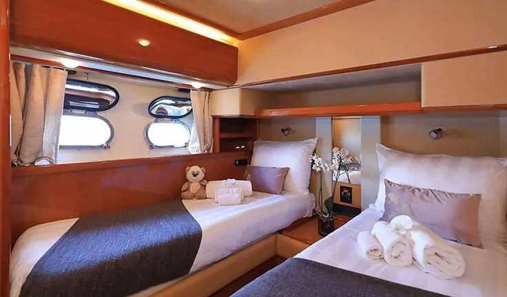 Quo Vadis I cabin twin berth aboard a yacht with portholes and wood accents