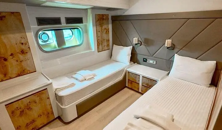 Angelo III cabin twin bed interior with sofa, desk, and porthole window