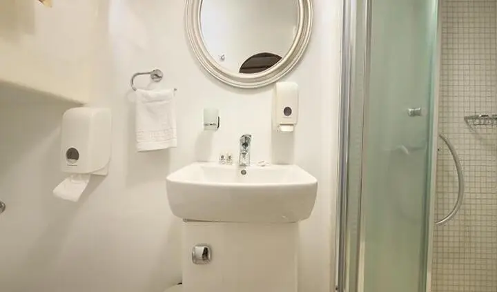 Linda yacht cabin interior with round mirror, white sink, and glass shower