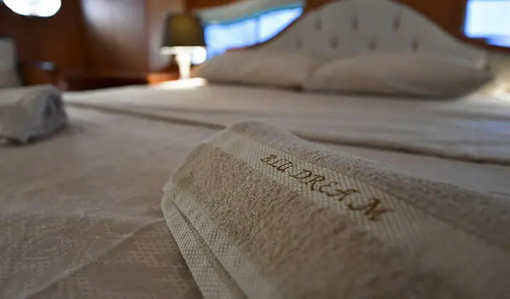 Master cabin with king bed and plush headboard, beige linens, and ensuite door