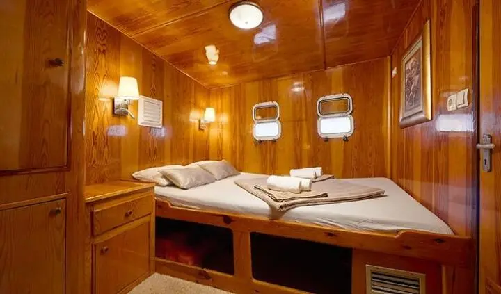 Linda yacht cabin with two single beds, wooden panels, small mirror, reading lights