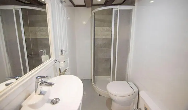 Compact master cabin with king bed, ensuite shower, and circular doorway