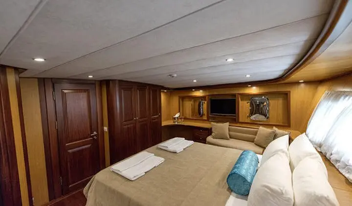 Master cabin with king bed, beige linens, wooden cabinetry and seating area