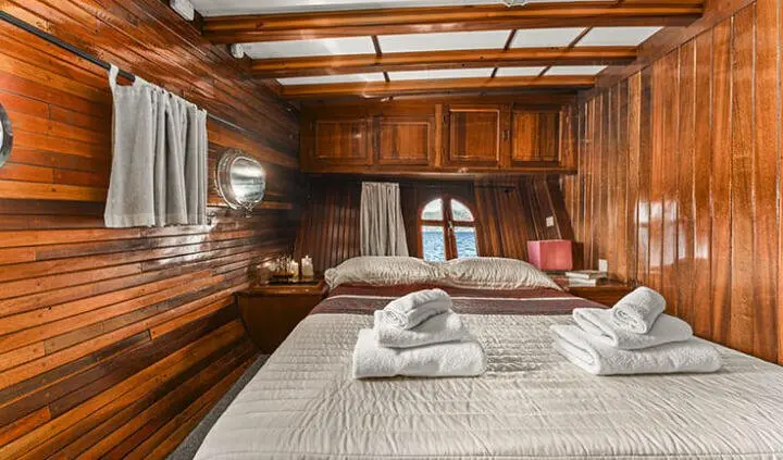 Cozy wooden cabin aboard a yacht with cushioned seating and folded towels