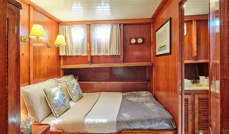 Compact cabin with double bed, wooden paneling, shelves and window