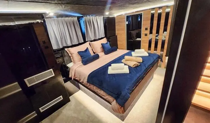 Master cabin with king bed, blue bedding, beige headboard, and ensuite door