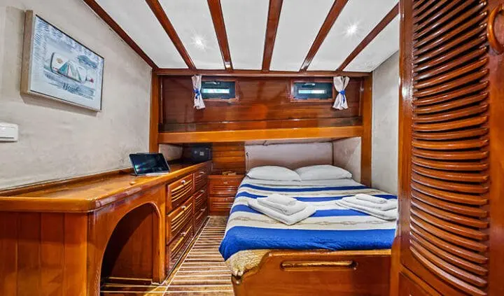 Interior cabin on Eleganza gulet with wood panels, bed, and striped bedding