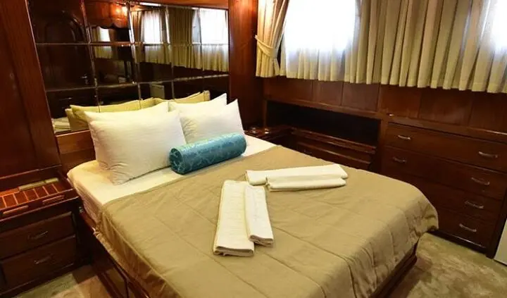 Master cabin with king bed, beige linens, brown headboard, bedside lamps