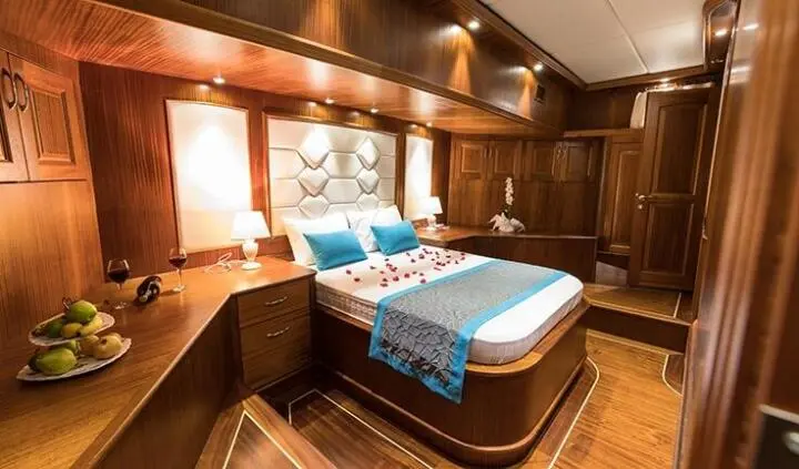 Vista Mare master cabin with king bed and ensuite, wood paneling and blue accent linens