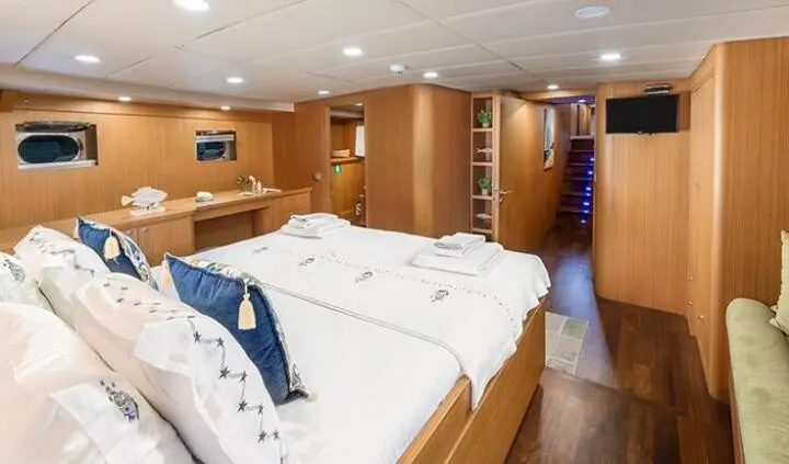 Artemis yacht master cabin with king bed, wood panels, ensuite doorway