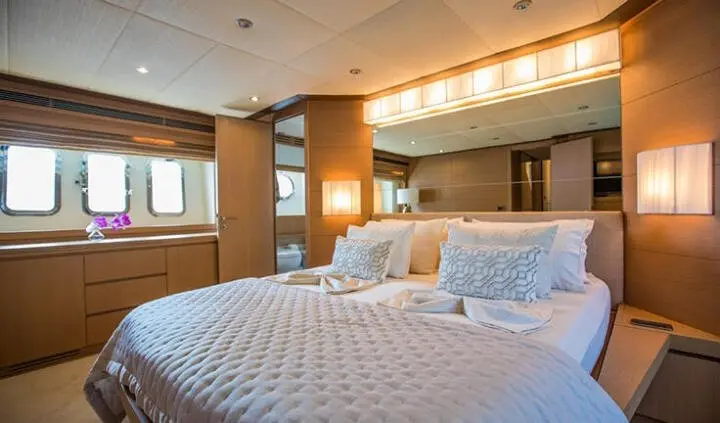 Master cabin with king bed, white linens, bedside lamps and ensuite door