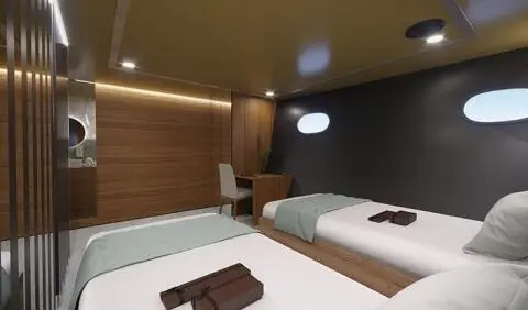 Twin cabin interior with wood paneling, two beds, and pillows