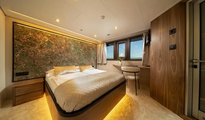 Master cabin with king bed, white bedding, wood panels, ensuite hints, warm lighting