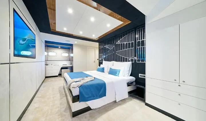 A bright cabin with a neatly made bed, blue accents, and windows