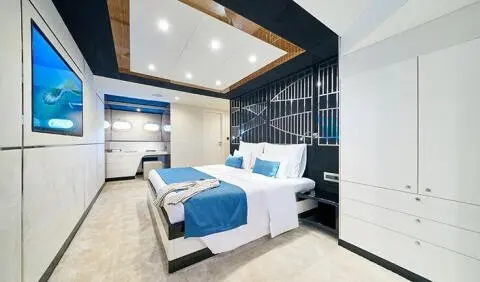 A bright cabin with a neatly made bed, blue accents, and windows