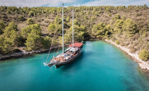 Croatia 32m luxury sailing yacht anchored in turquoise inlet amid pine-covered cliffs