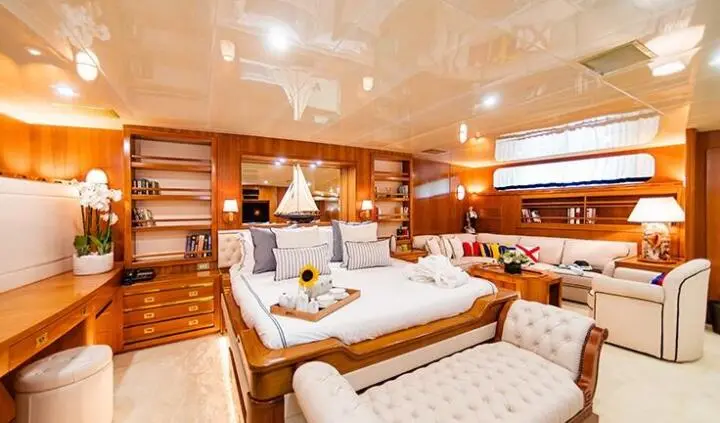 Wind Of Fortune master cabin with large bed, wood panels, and bedside seating