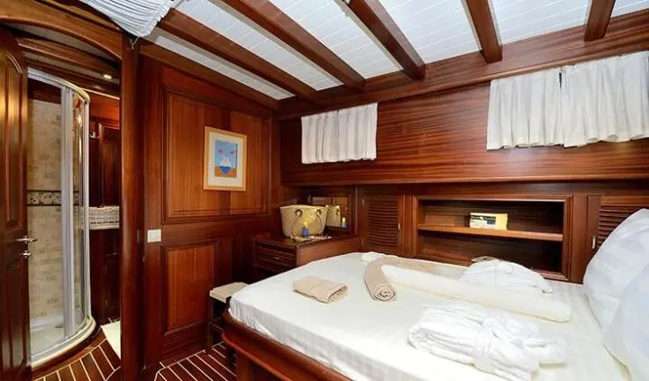 Cozy wooden cabin aboard Samarkand with double bed, ports, and towels