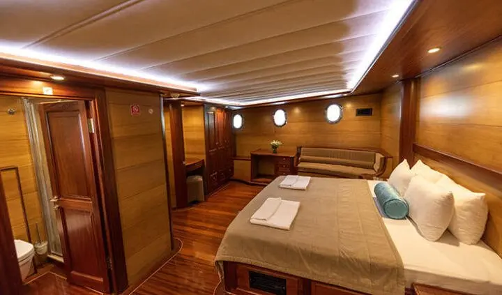 Master cabin with wood paneling, large bed, and ensuite layout on yacht Kayhan 4