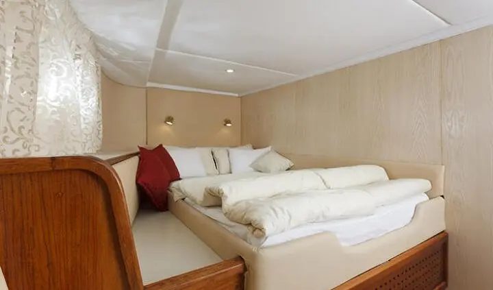 Double en-suite cabin with two single beds, beige walls, and red throw pillows