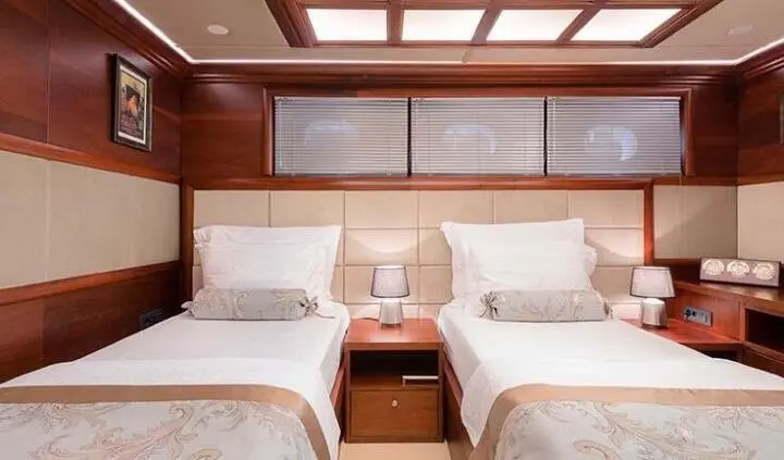 Twin cabin on Lady Gita: two single beds with beige bedding and wooden headboard