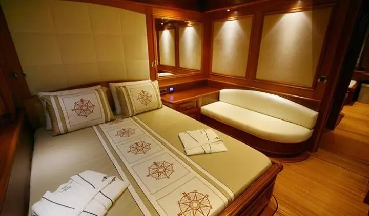 Cozy yacht cabin with wooden walls, double bed and patterned bedspread