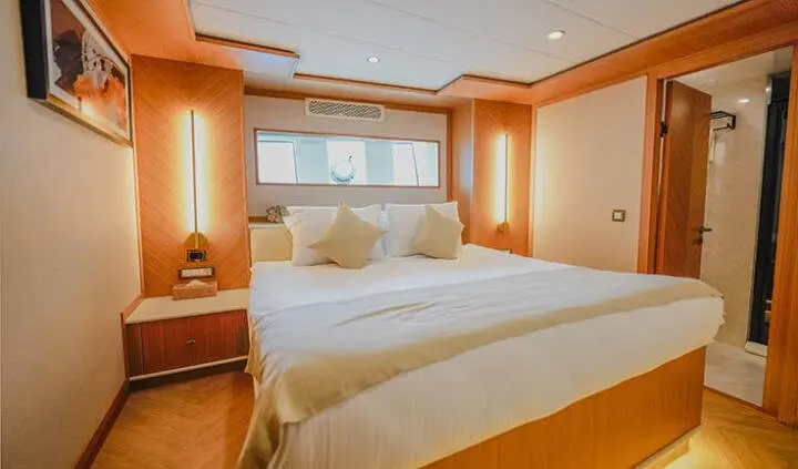 King Of The Sea master cabin with two white beds and wood tones