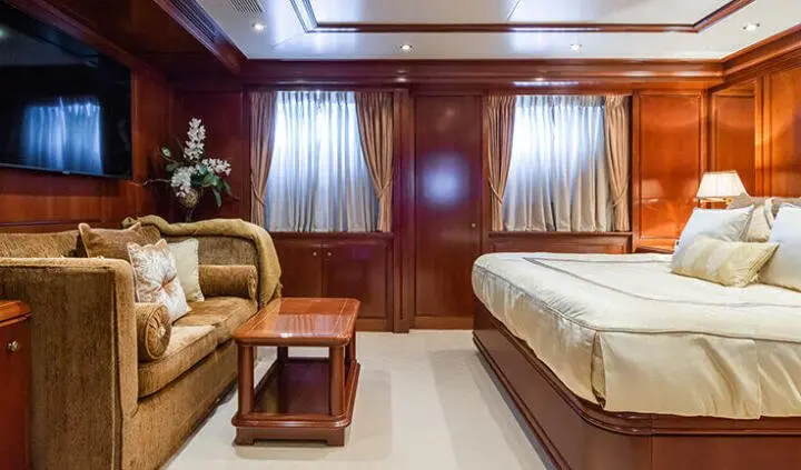 Master cabin with king bed, wood panels, bedside lamps, and seating area