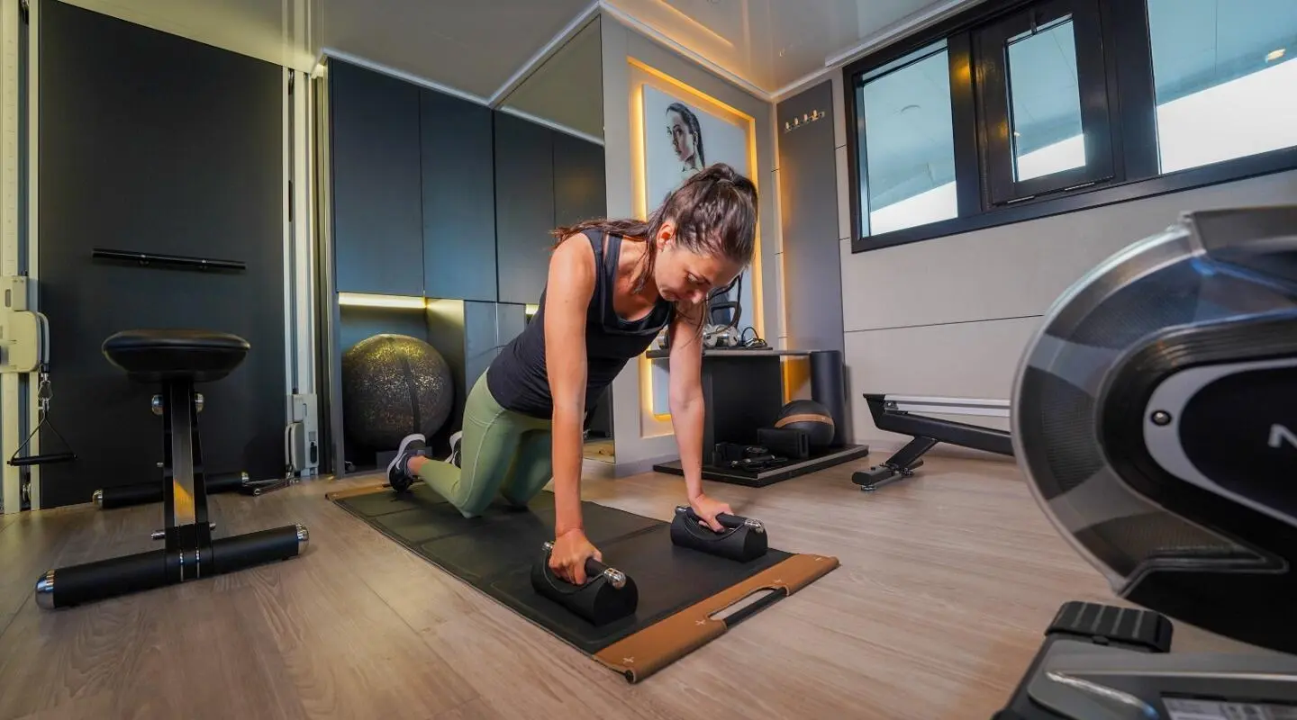 Interior deck yoga on Freedom yacht, woman in downward dog pose, modern teak floor
