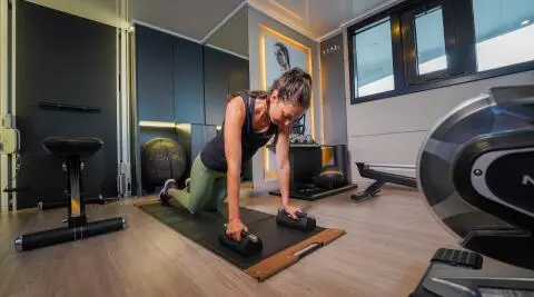 Interior deck yoga on Freedom yacht, woman in downward dog pose, modern teak floor