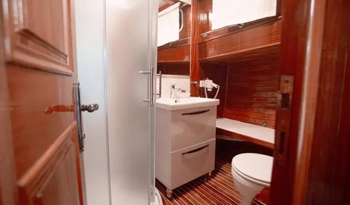 Cabin ensuite bathroom aboard Malena yacht, compact space with sink and toilet, wood cabinetry