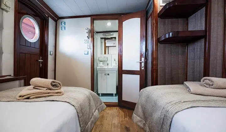 Twin cabin with wooden shelving and two beds, door front, compact space