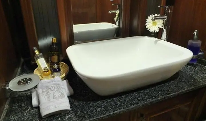 A large white freestanding bathtub sits in a dark wood en-suite with marble countertop