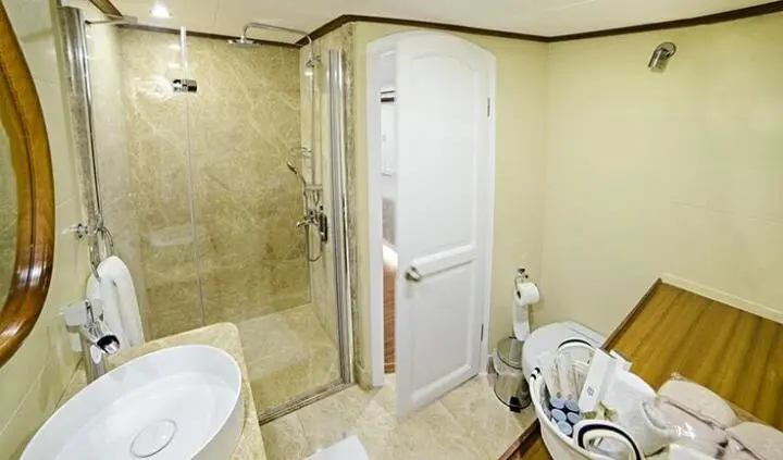 Master cabin with king bed, ensuite door, beige walls, and tiled floor