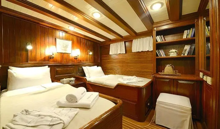Ecce Navigo cabin interior with wood panels, table set for dining, and built-in storage